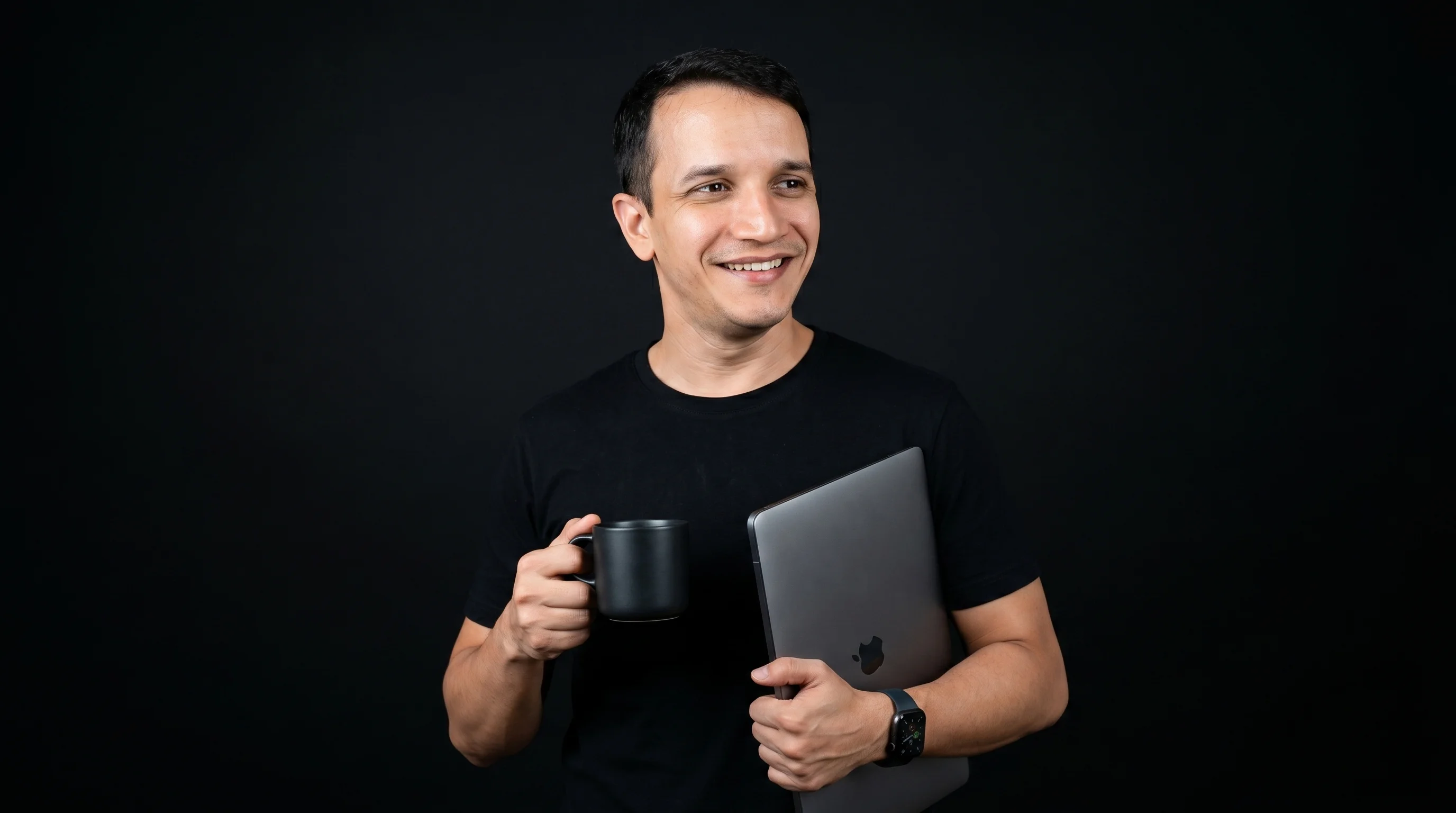Djean Moraes segurando um laptop e uma caneca de café